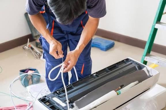 Technicians repairing an indoor air conditioning unit