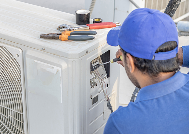Technician repairing a residential outdoor HVAC condenser for indoor comfort